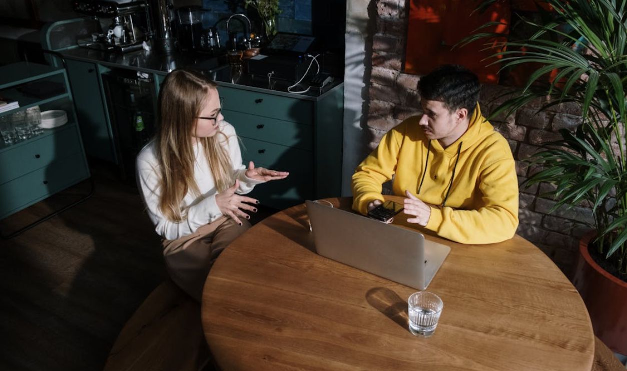 Man and Woman Sitting at Table Having a Conversation