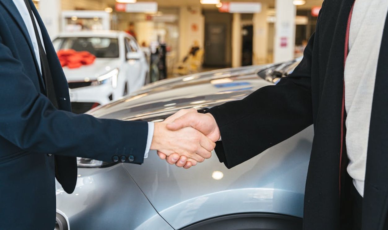 Close up of Men Shaking Hands and Cars in Background