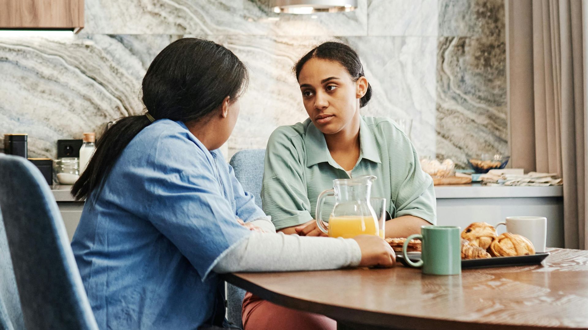 Two women enjoy a warm conversation over breakfast in a stylish kitchen.
