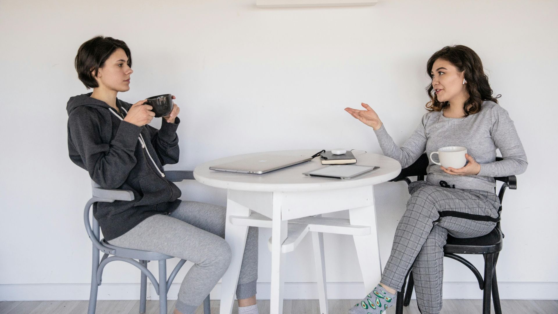 Two women enjoying a casual conversation with coffee in a cozy indoor setting, enhancing connections.