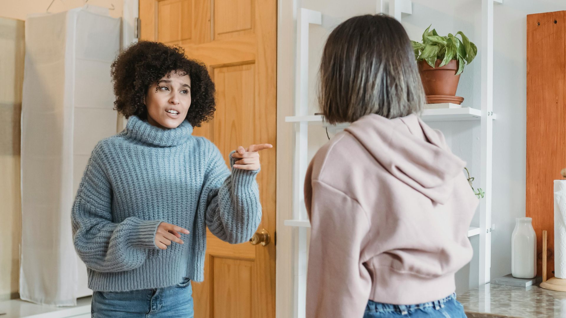 Two women having an expressive debate in a cozy apartment interior.