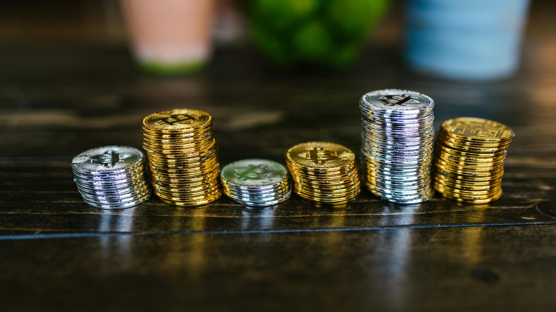 Pile of shiny gold and silver cryptocurrency coins on a wooden table.