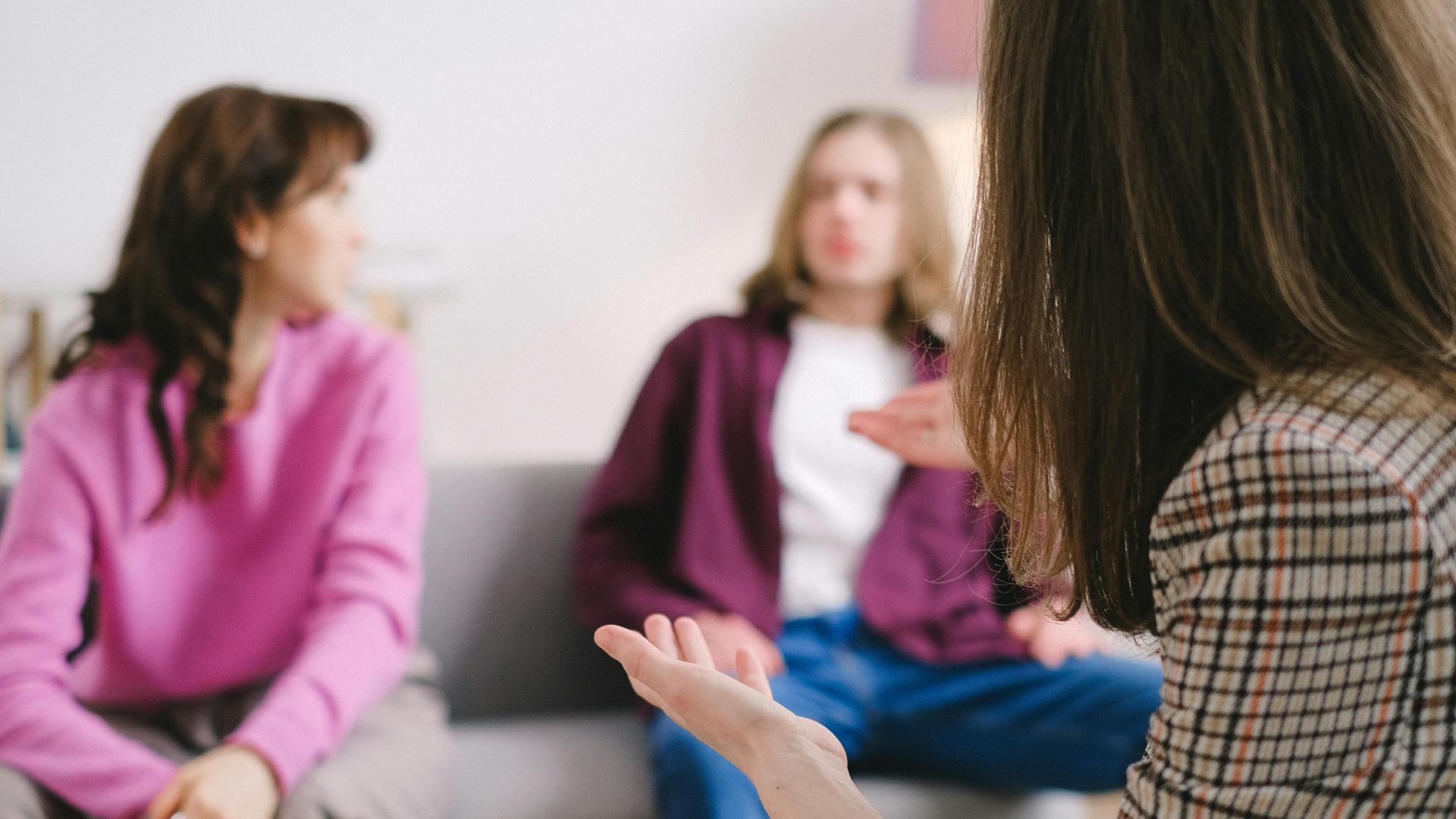 Engaged counseling session with three adults discussing together in a cozy indoor setting.