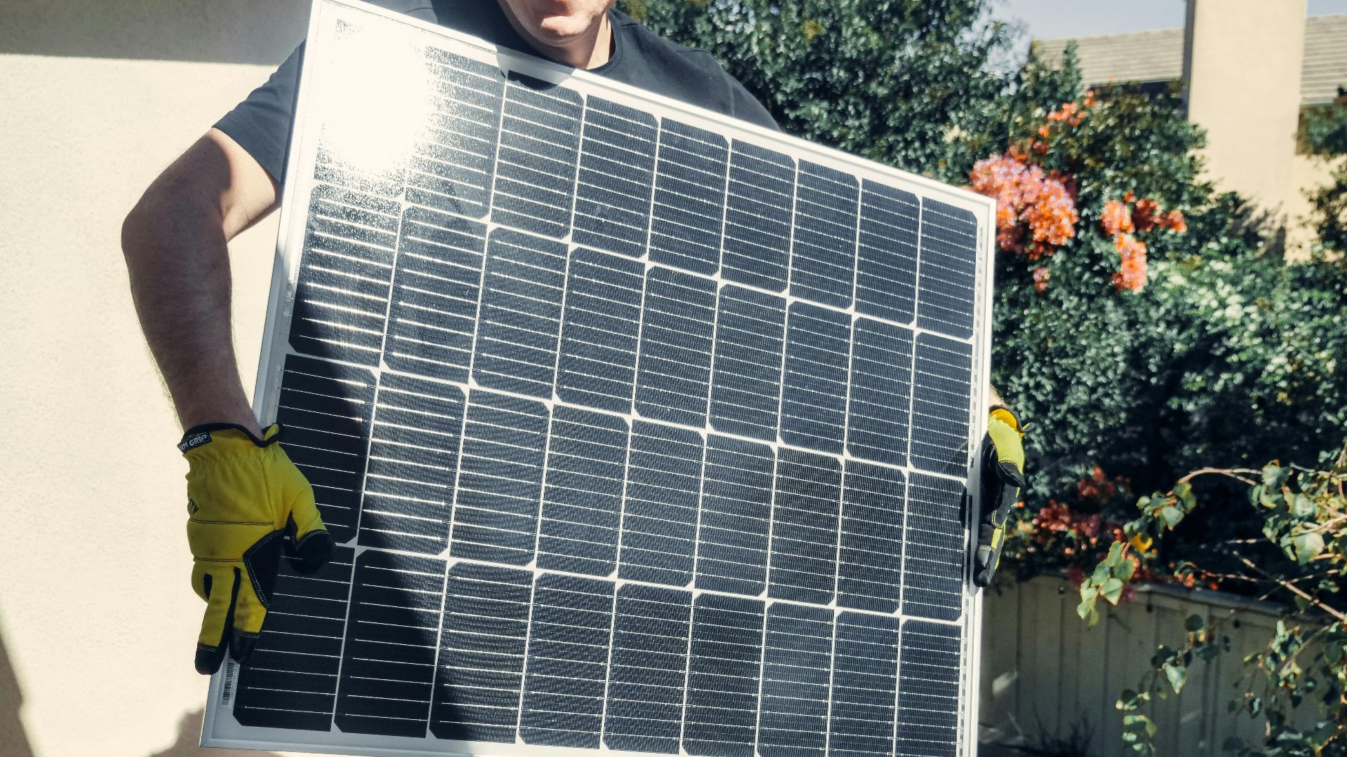 Technician carrying solar panel on rooftop. Clean energy installation outdoors.