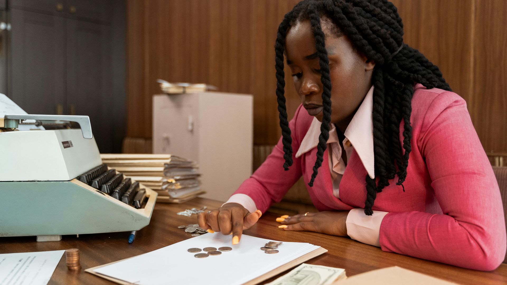 A businesswoman in vintage attire counts coins in a retro office setting.