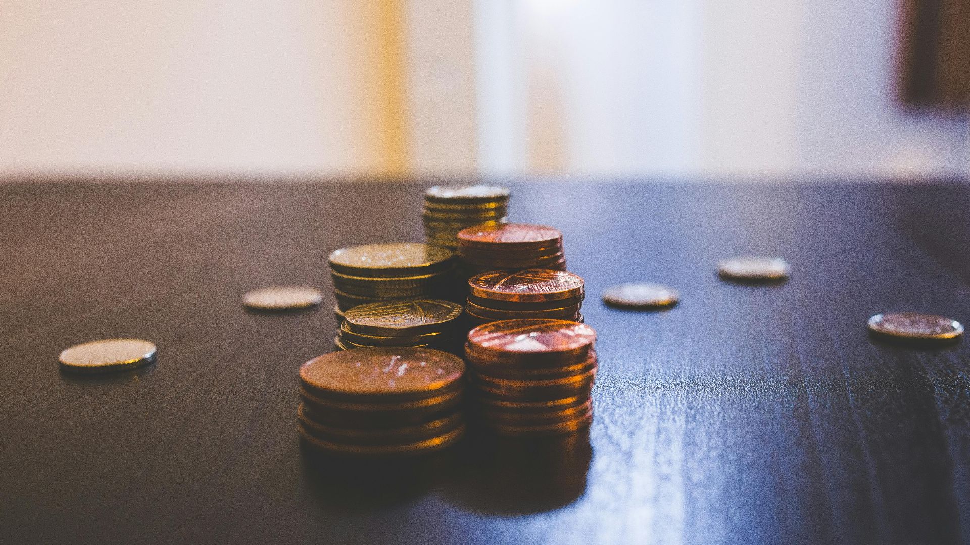 Close-up of various coins stacked on a dark table indoors.