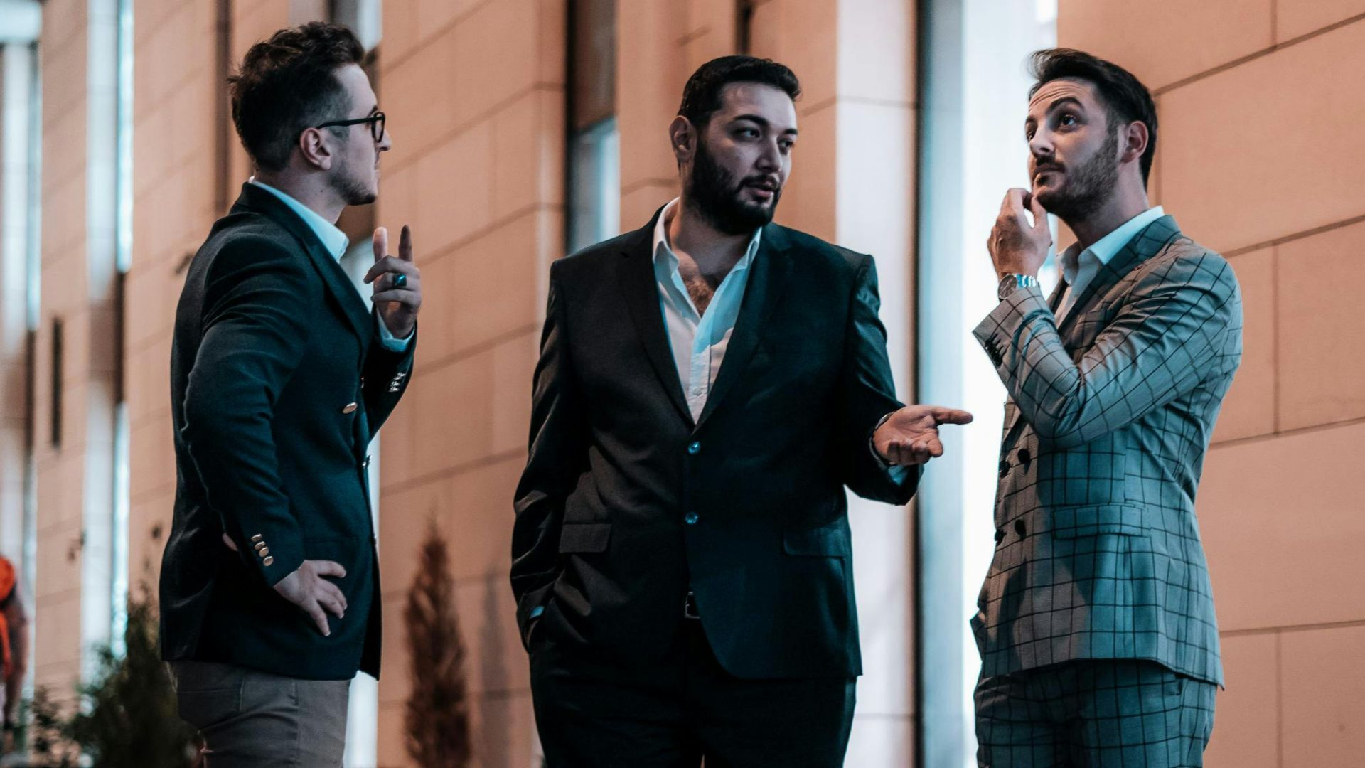 Well-dressed businessmen having a conversation outside during twilight on a city street.