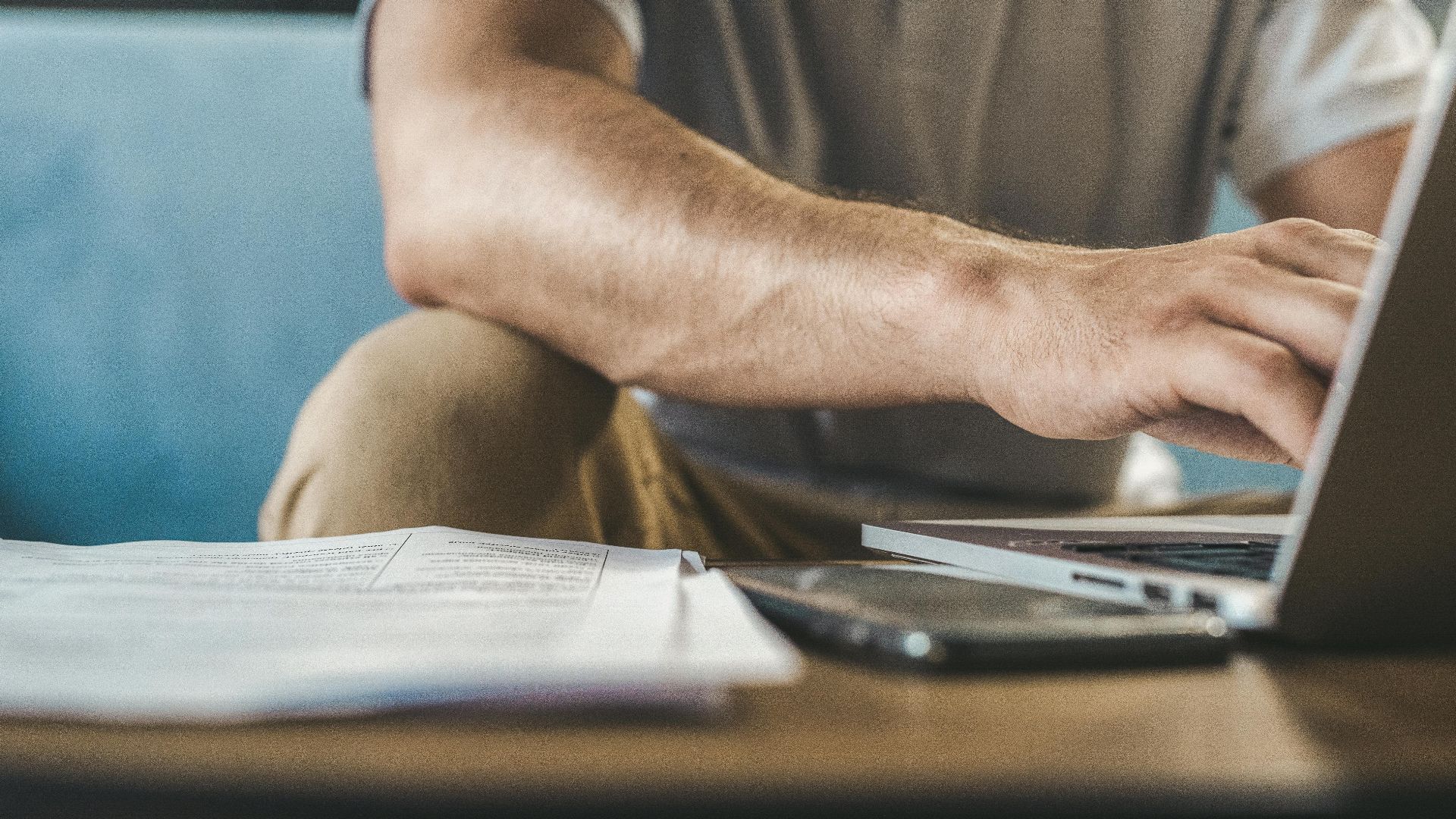 A man typing on a laptop at home, using wireless technology.