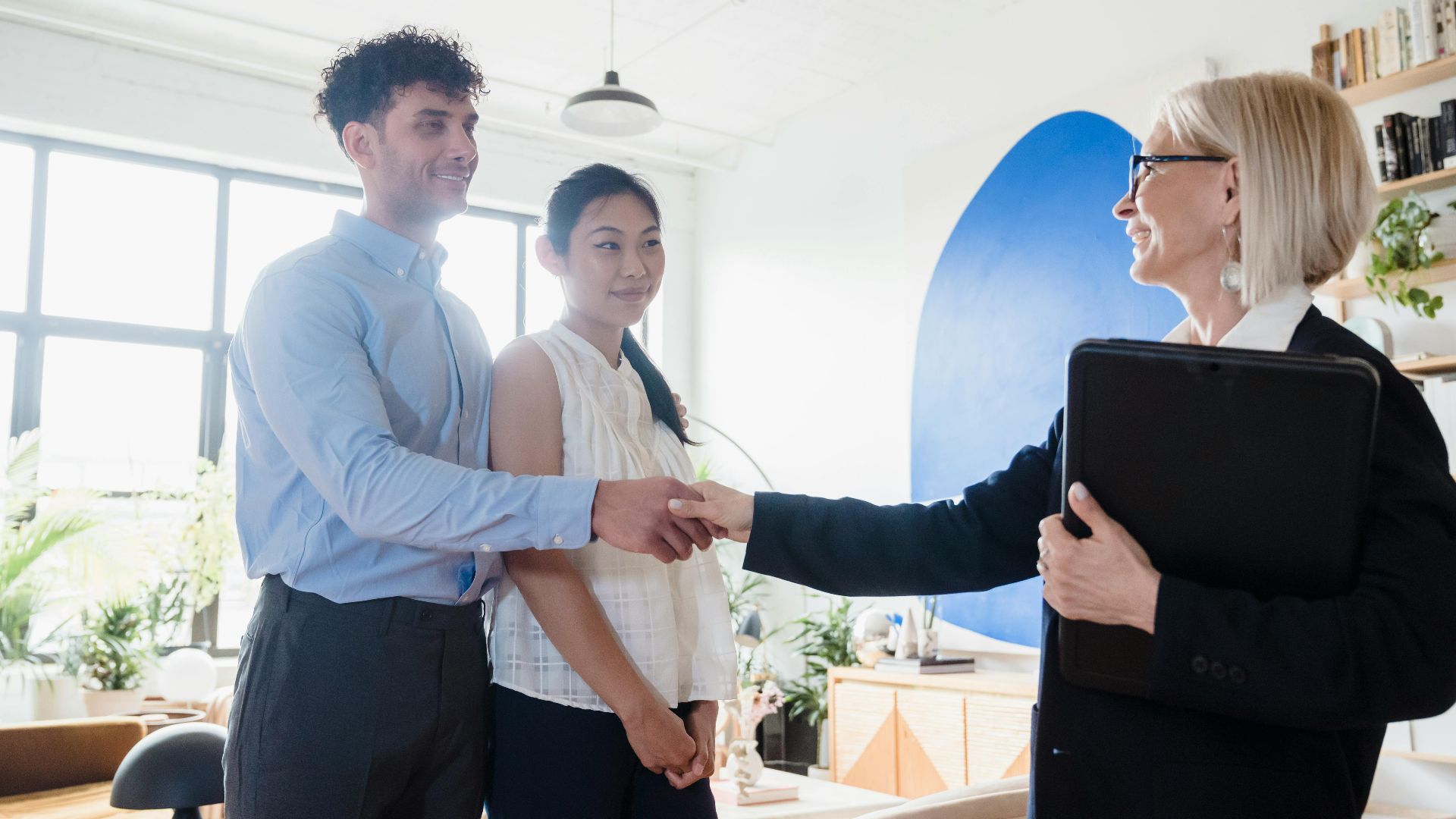 A business deal is finalized with a handshake between diverse professionals in a contemporary office.