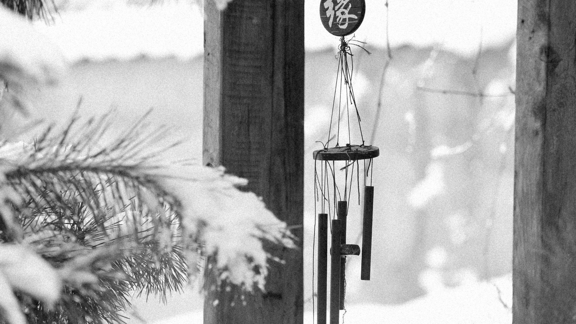 Serene black and white winter scene featuring a hanging wind chime outdoors.