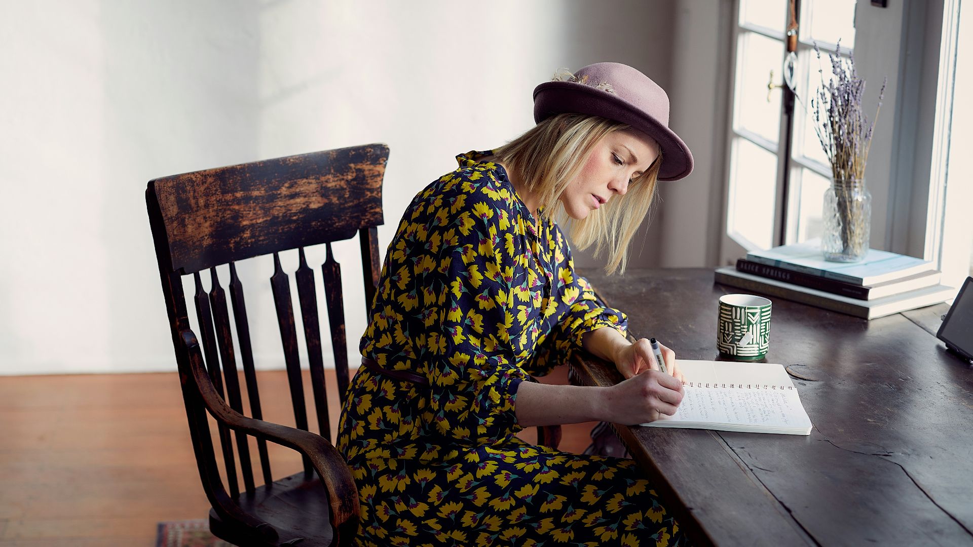 woman in yellow and black floral dress sitting on brown wooden chair