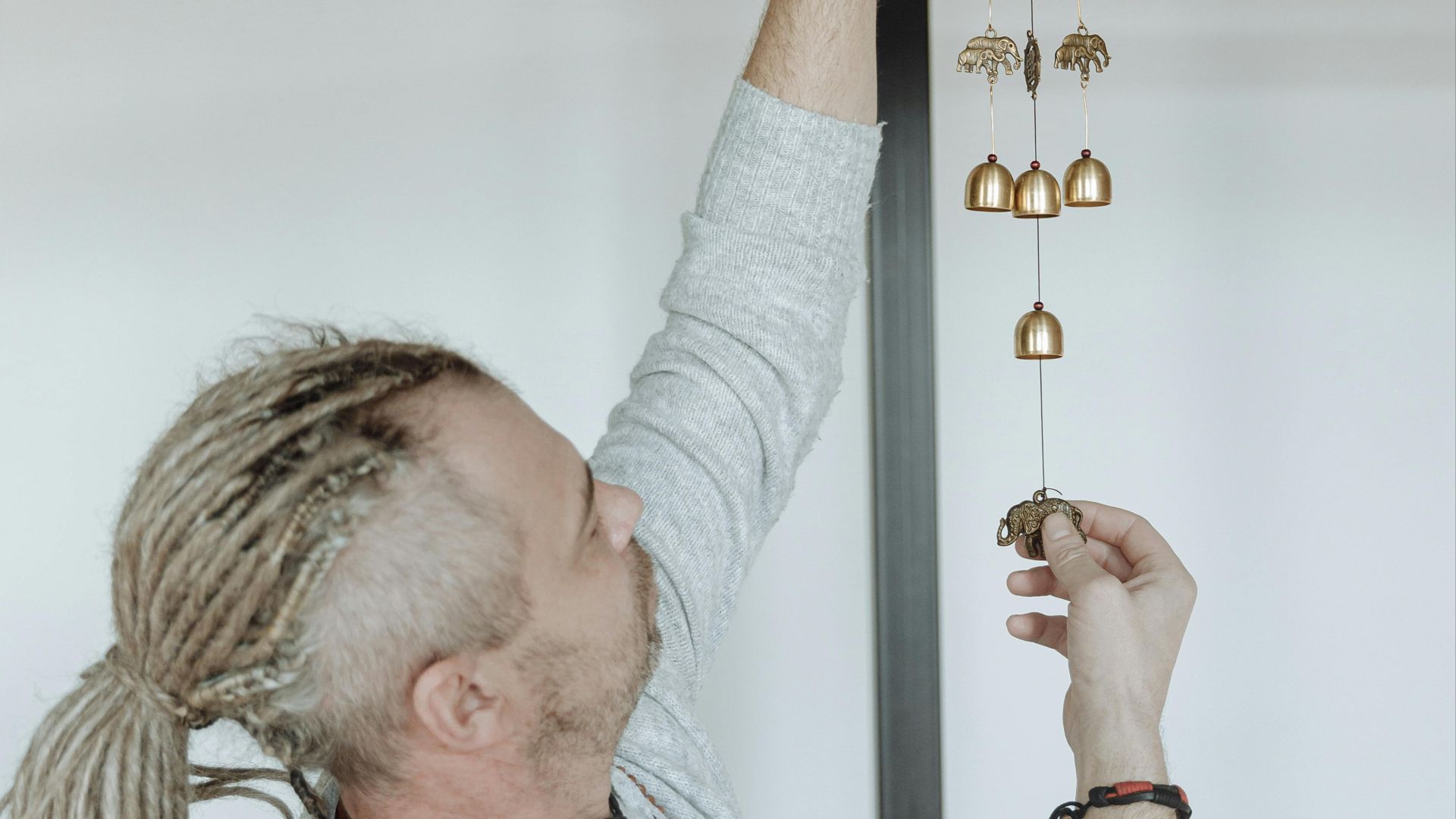 A person decorates indoor space with hanging bells, adding a touch of charm.