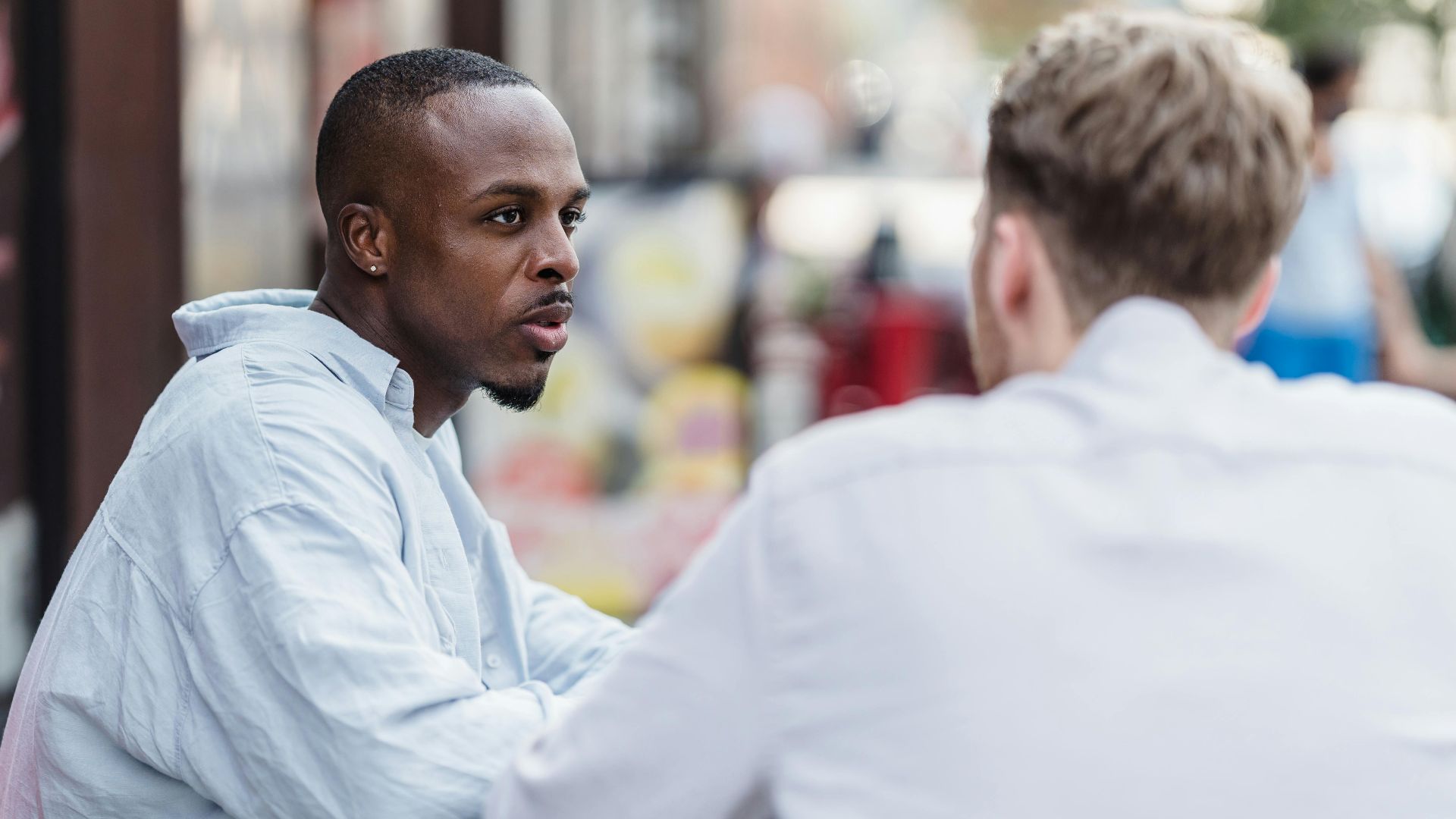 Two men having a conversation in an outdoor setting on a sunny day.