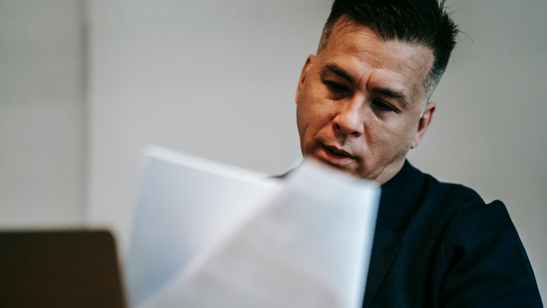Professional man intently reviewing paperwork at his workstation indoors.