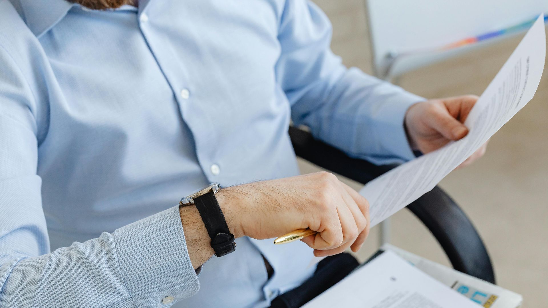 Businessman reviewing papers in office setting, highlighting analysis and attention to detail.