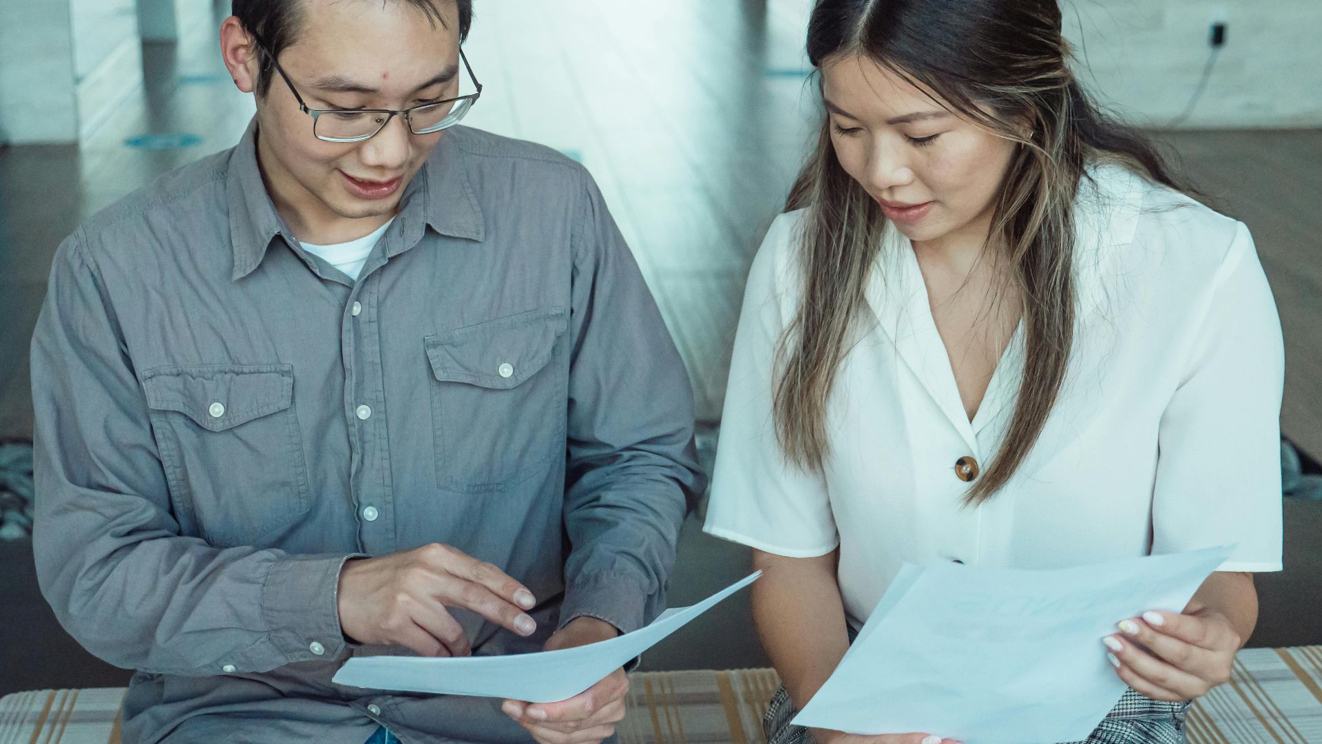 Two coworkers reviewing documents in a modern office, focused on teamwork and planning.