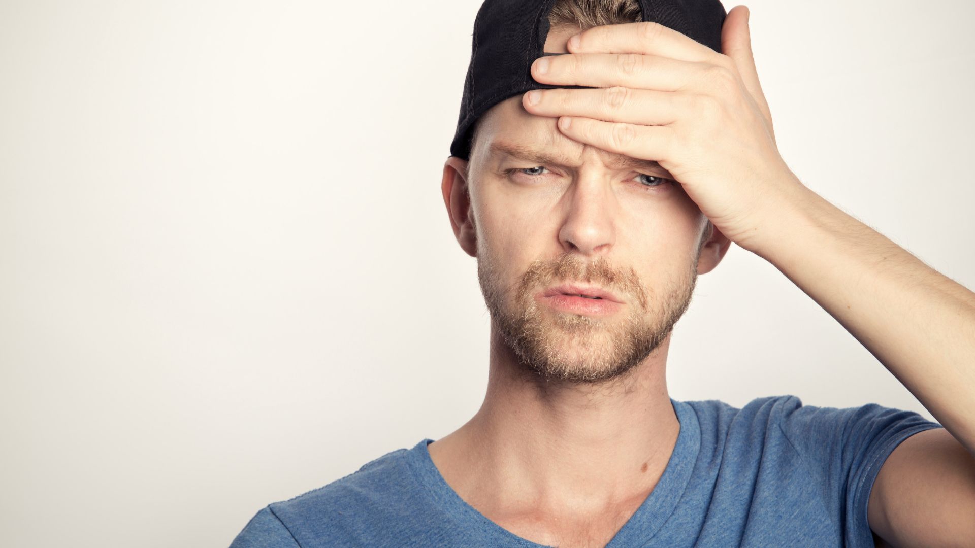 man in blue crew neck shirt covering his face