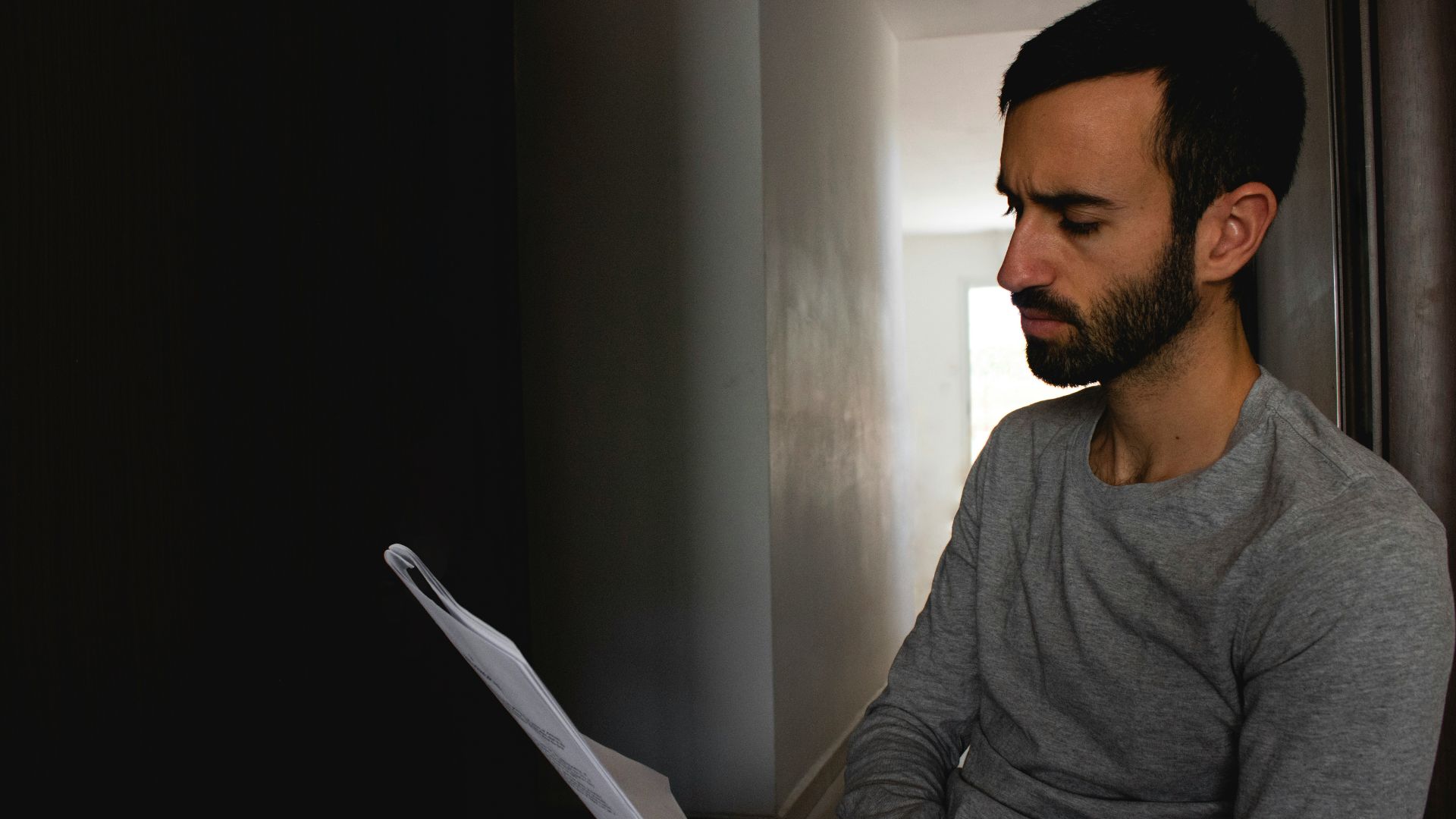 man in gray crew neck shirt holding white printer paper