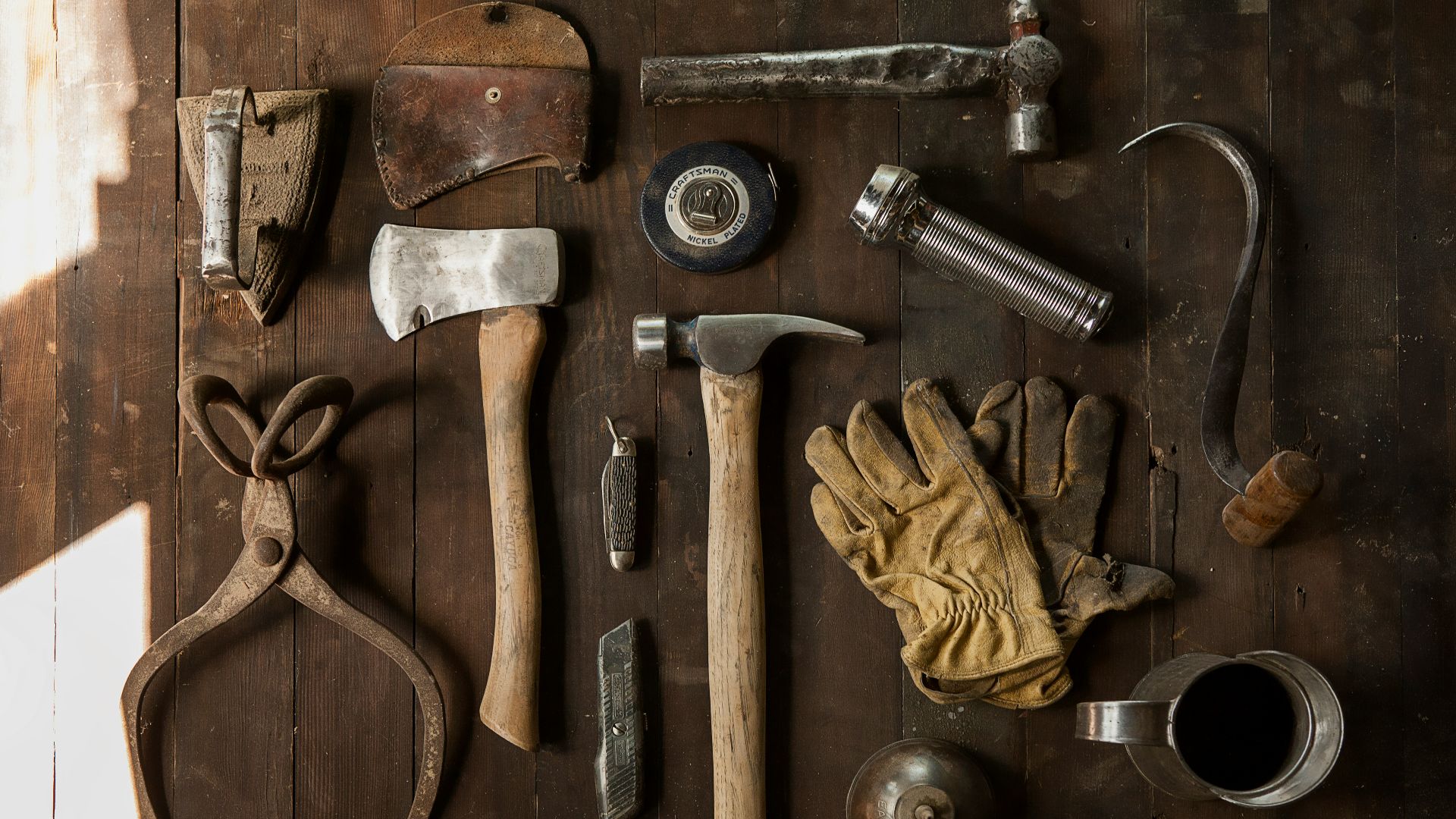 clothes iron, hammer, axe, flashlight and pitcher on brown wooden table