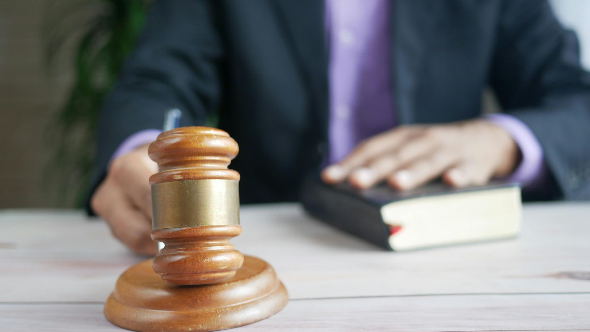 A wooden gavel and legal book represent justice in a court setting, emphasizing order and legal authority.