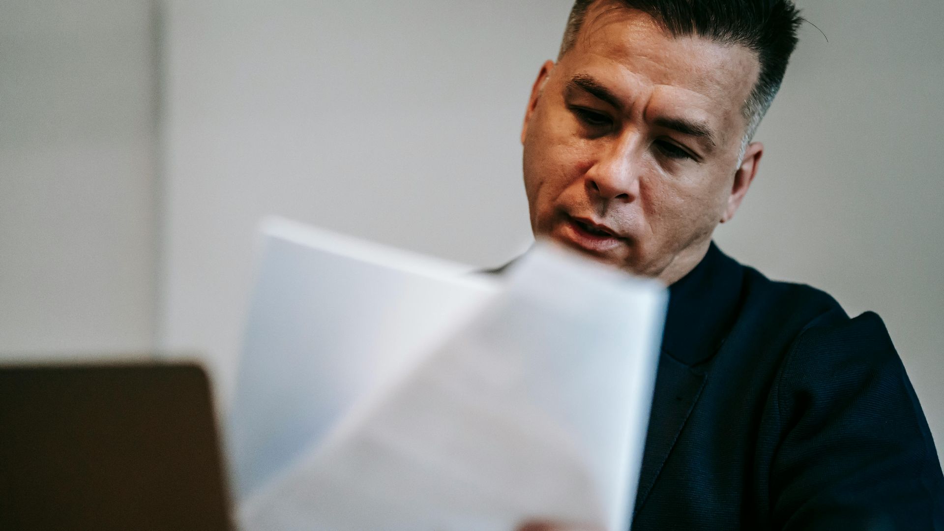 Professional man intently reviewing paperwork at his workstation indoors.