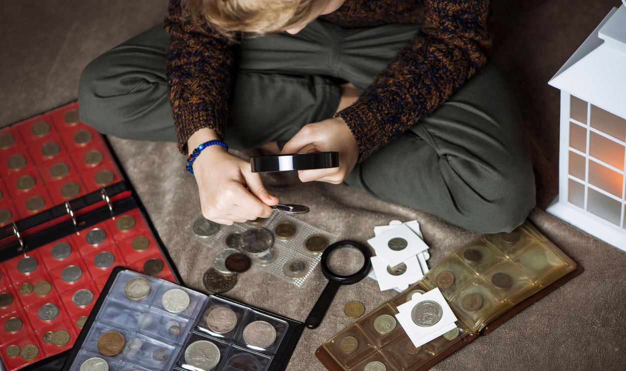 Numismatist boy looking old coin collection of rare coins