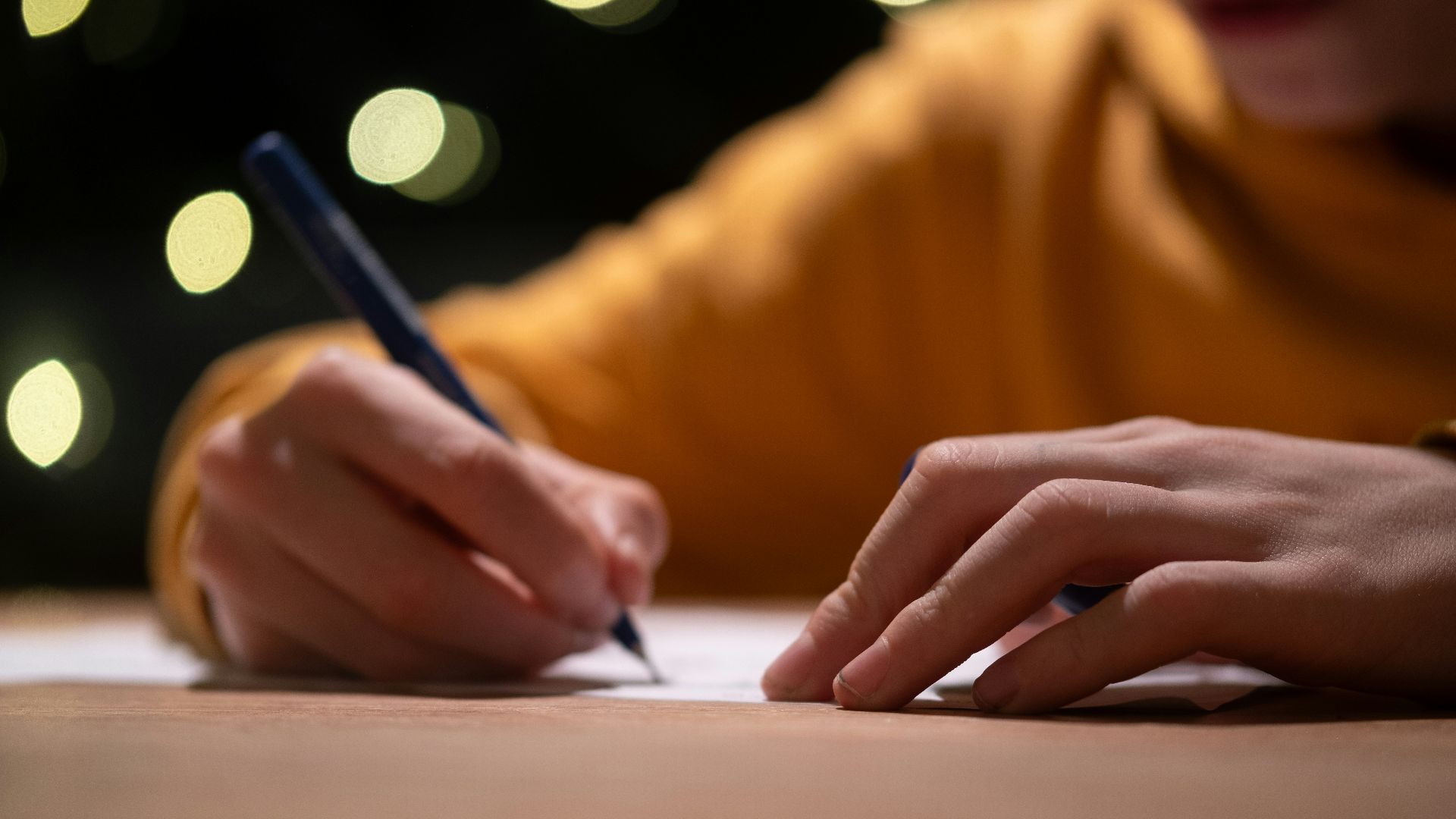 A person writing on a piece of paper with a pen