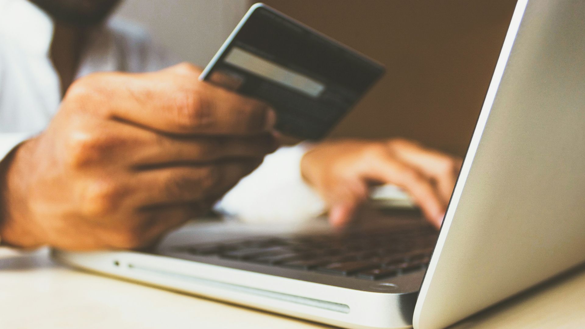 person using laptop computer holding card