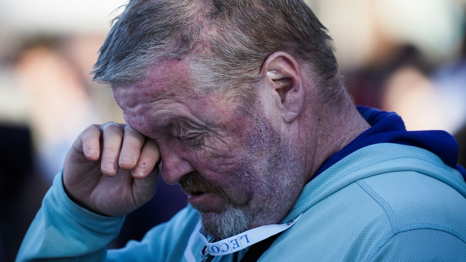 man in blue polo shirt holding his face
