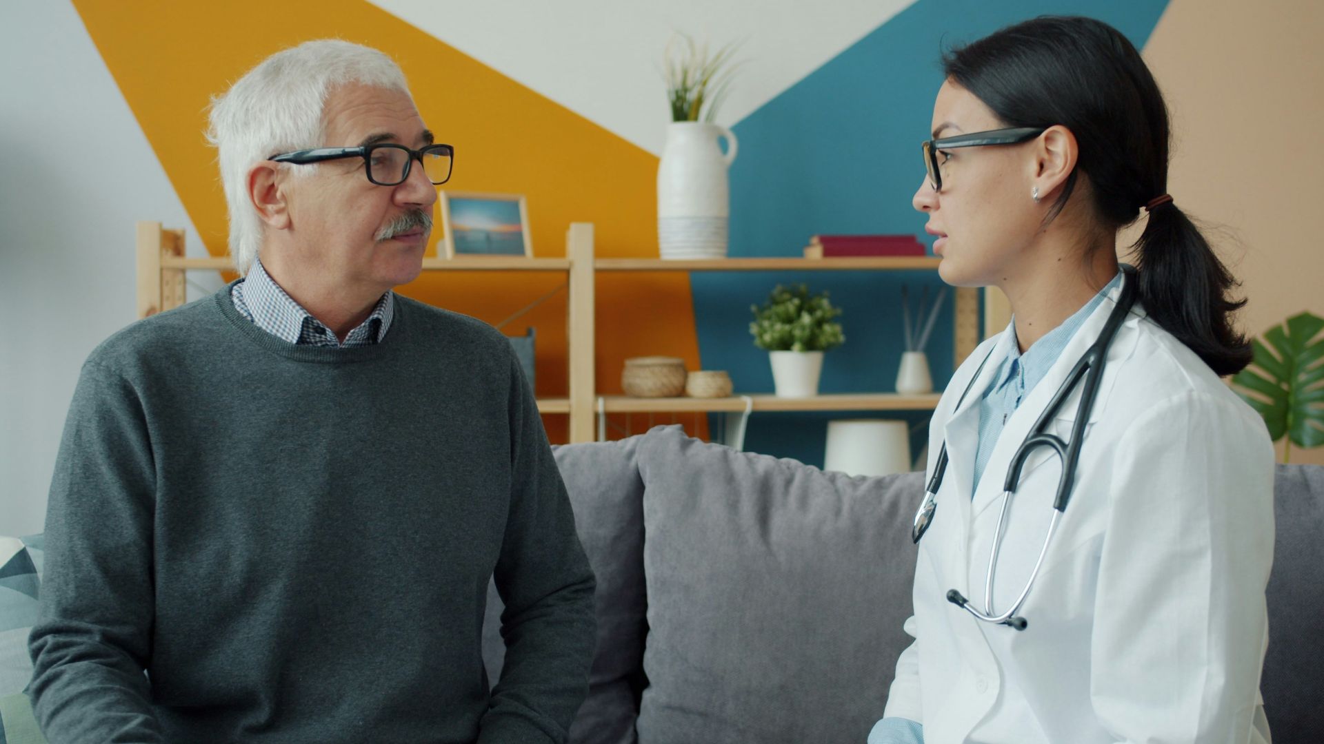 Doctor consults with an elderly patient on a couch.
