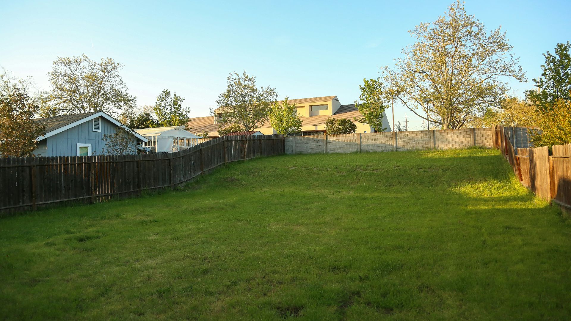 a grassy yard with a fence and a house in the background