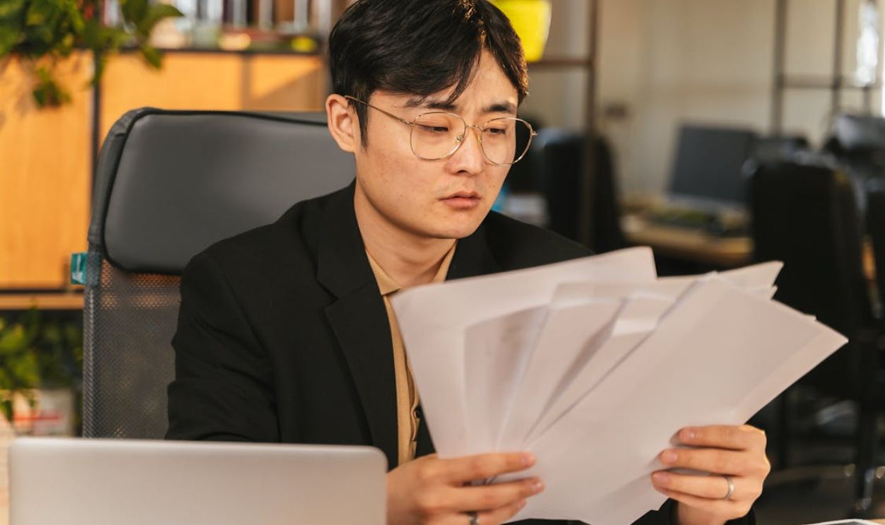 A Man in Black Suit Holding Paper Documents