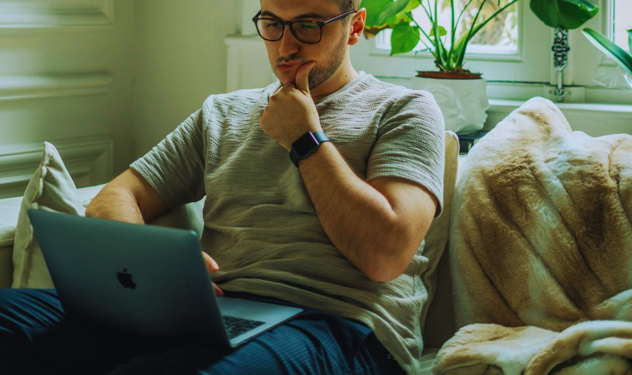 Photo of a Man in a Gray Shirt Working on His Laptop
