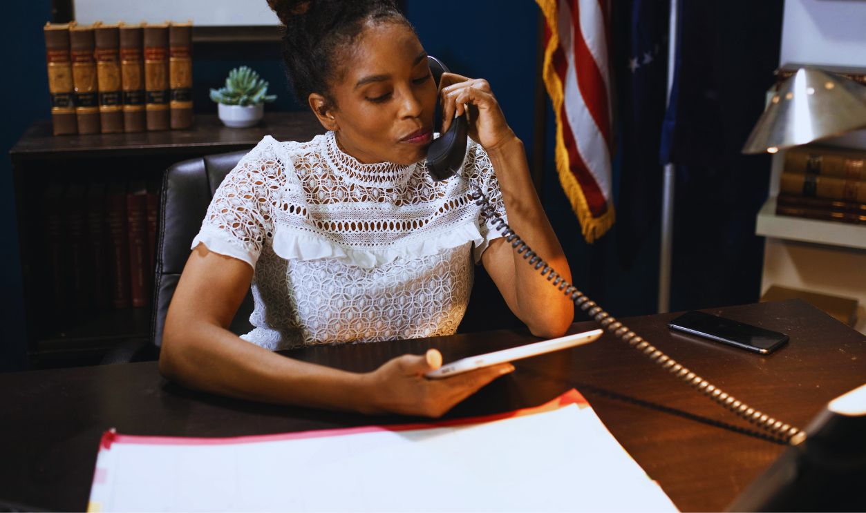 A Woman in White Shirt Sitting on a Chair while Talking on the Phone