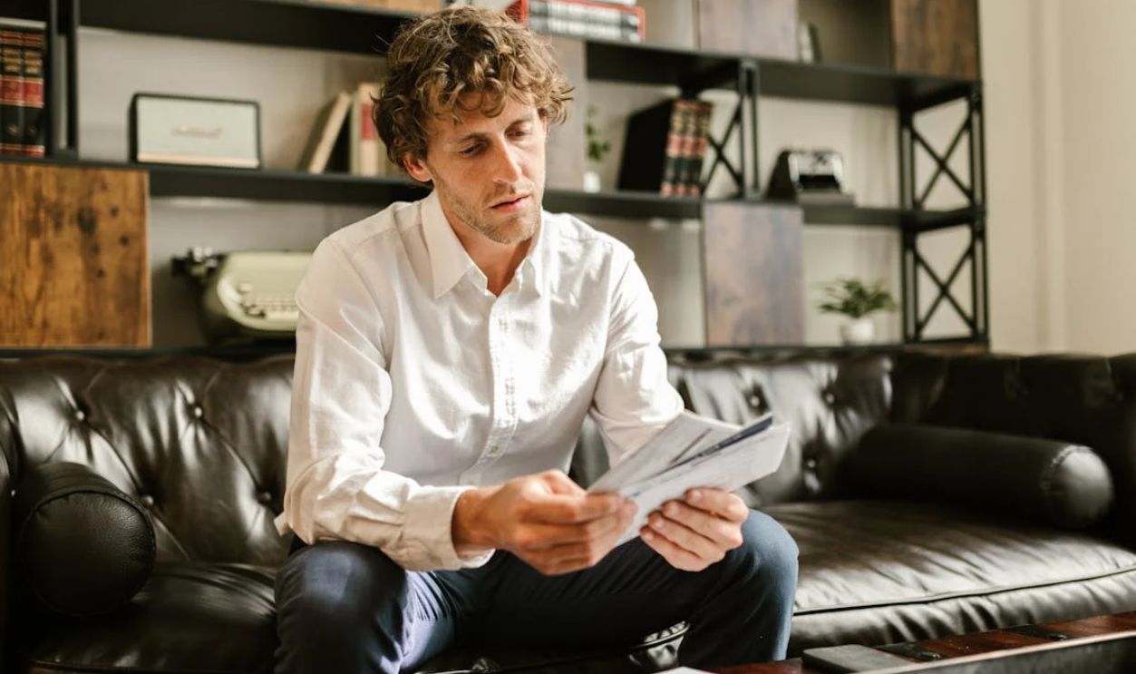 Man in White Long Sleeve Shirt Sitting on Sofa
