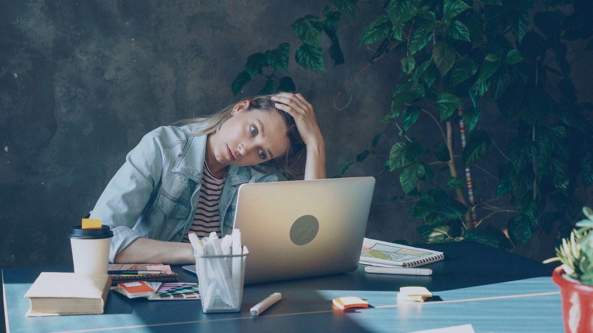 A woman appears stressed while working on laptop.