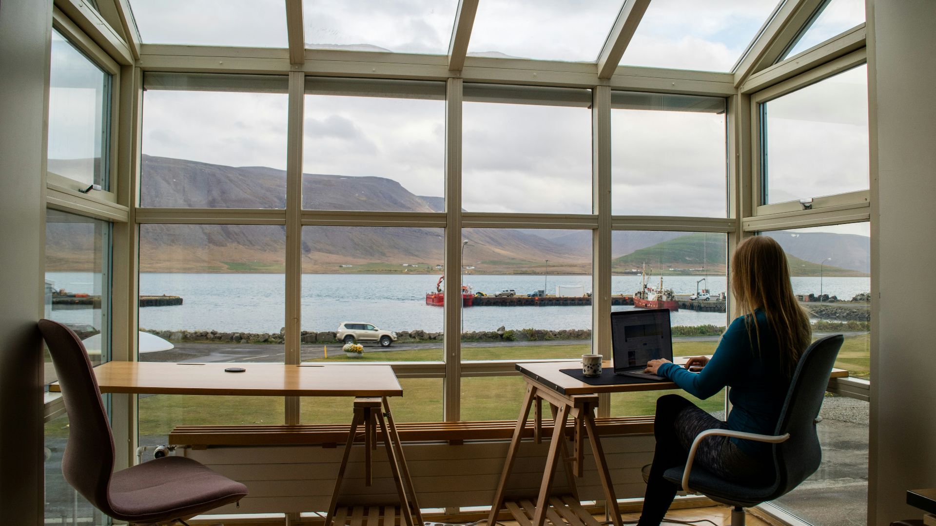 person in blue jacket sitting on brown wooden chair near brown wooden table during daytime