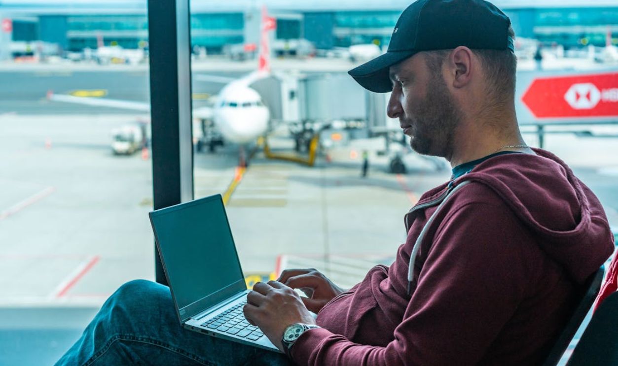 Man in Hoodie Jacket Sitting on a Chair Using Laptop