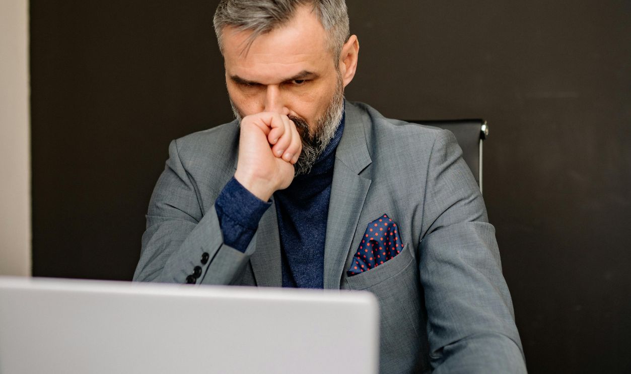 A Bearded Man in a Suit Using His Laptop