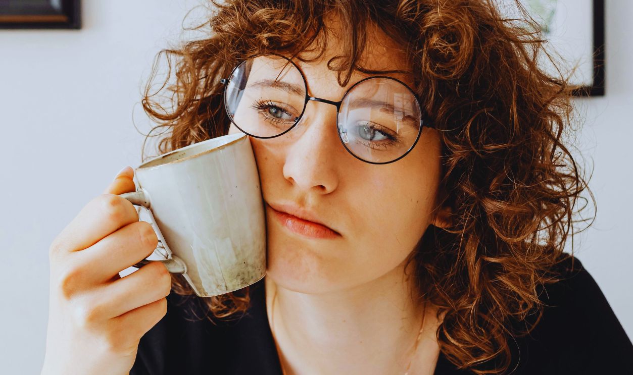 Woman in Black V-Neck Shirt Looking Unhappy while Holding a Mug