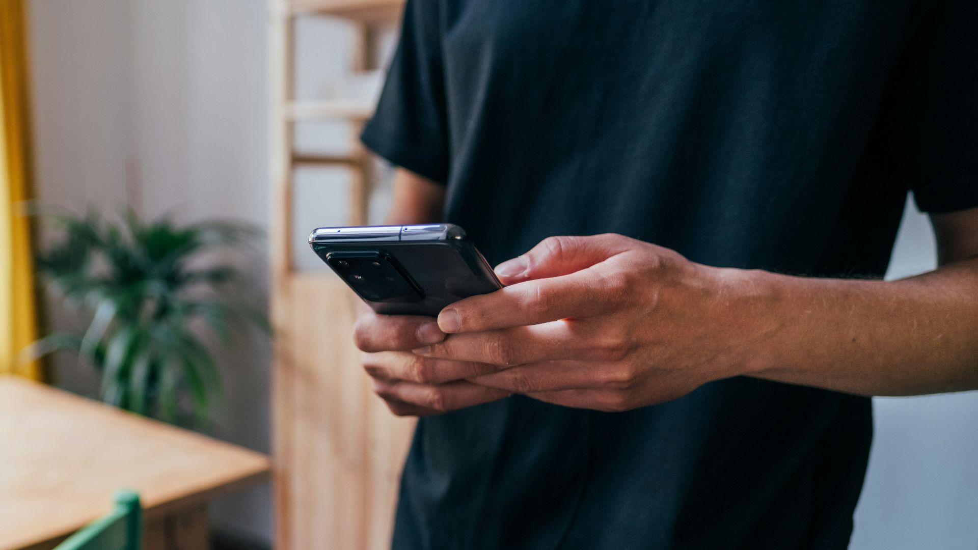 person in blue long sleeve shirt holding black smartphone