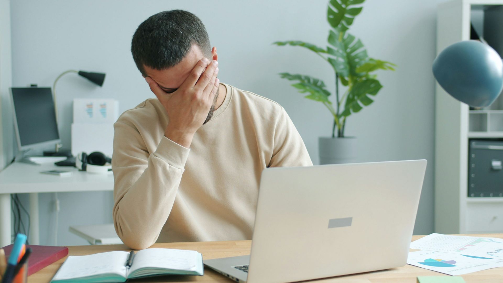 Man rubbing his face in front of laptop.