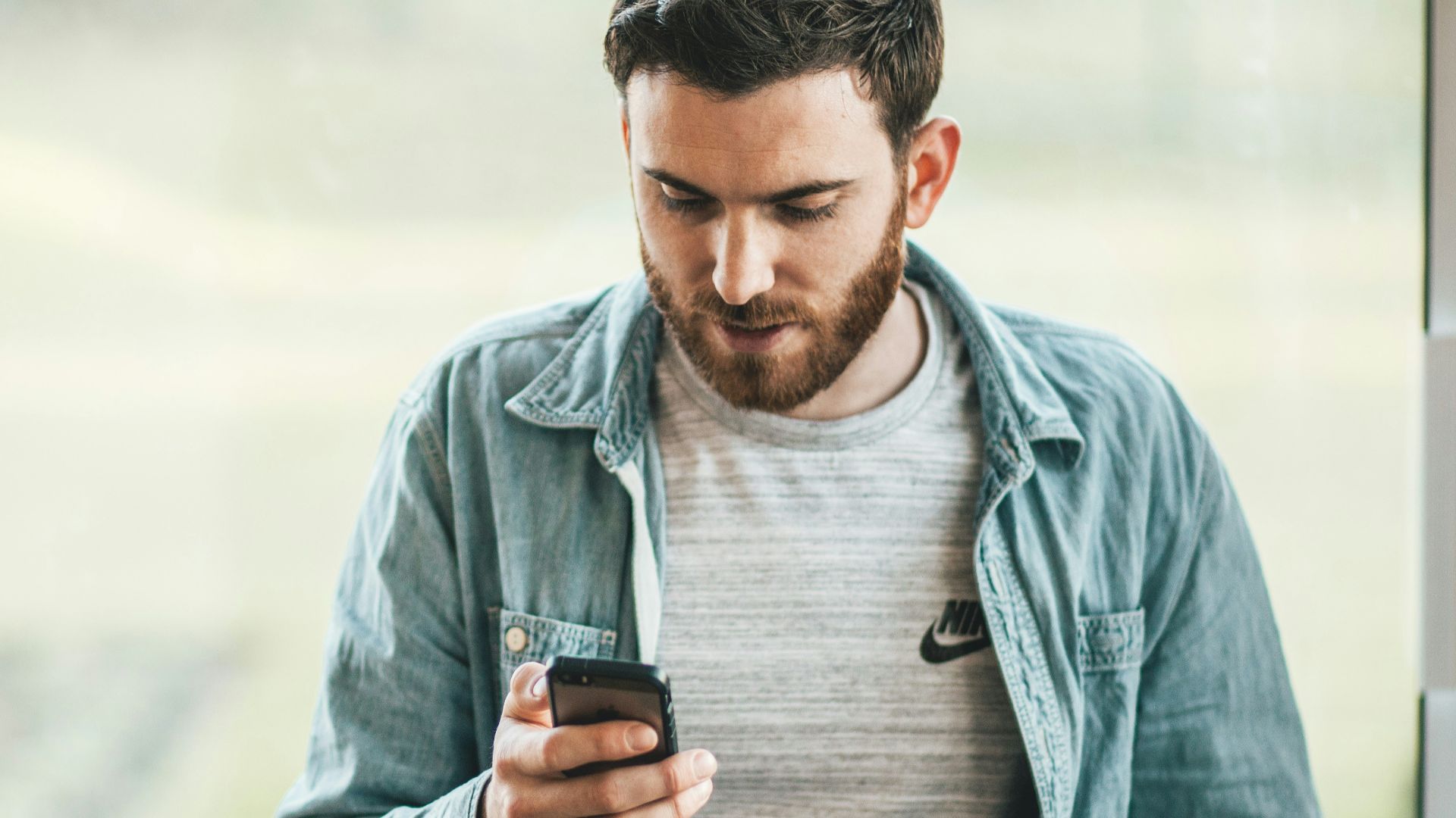 man holding a smartphone near the window