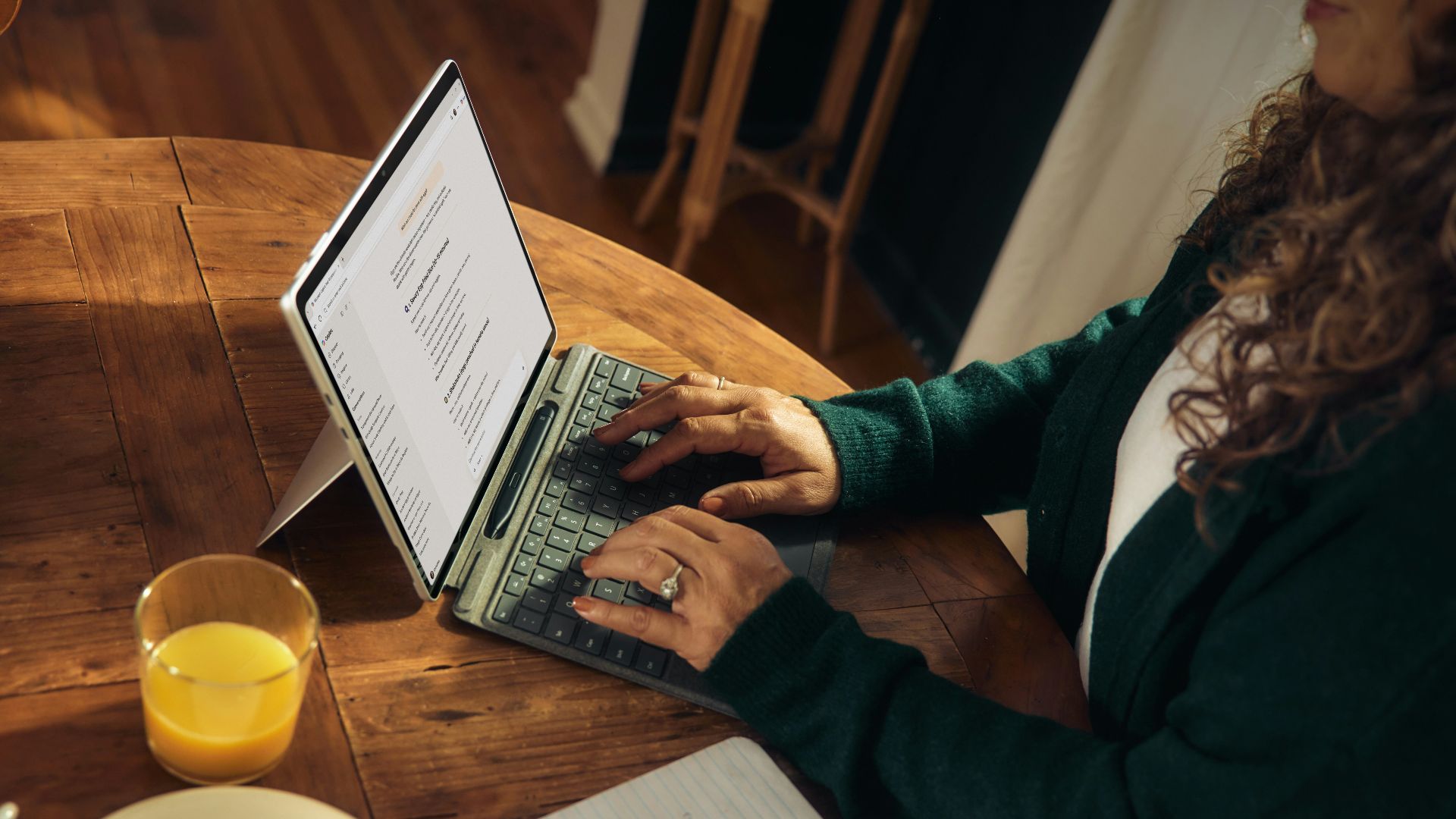 Woman typing on laptop at wooden table with breakfast.