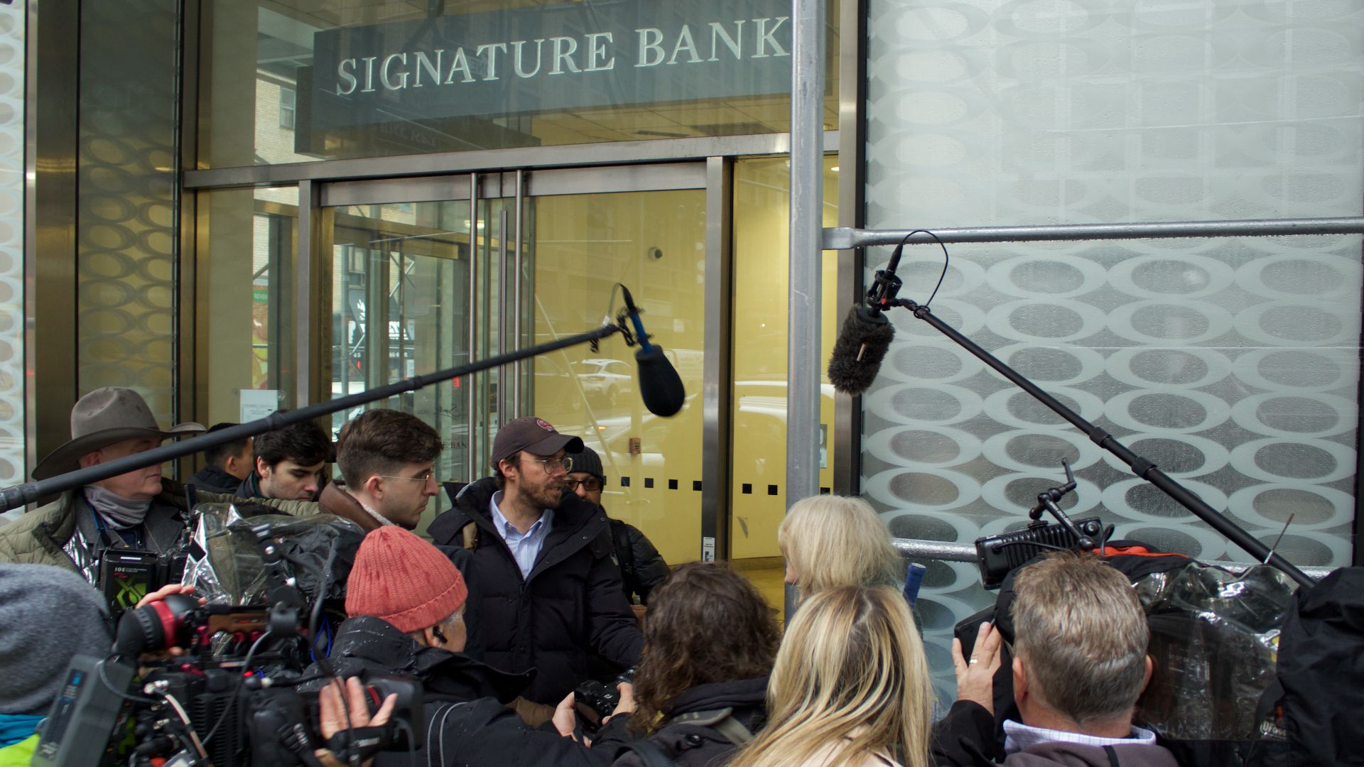 Reporters swarming a bank customer to ask questions. (She was fine answering questions.)