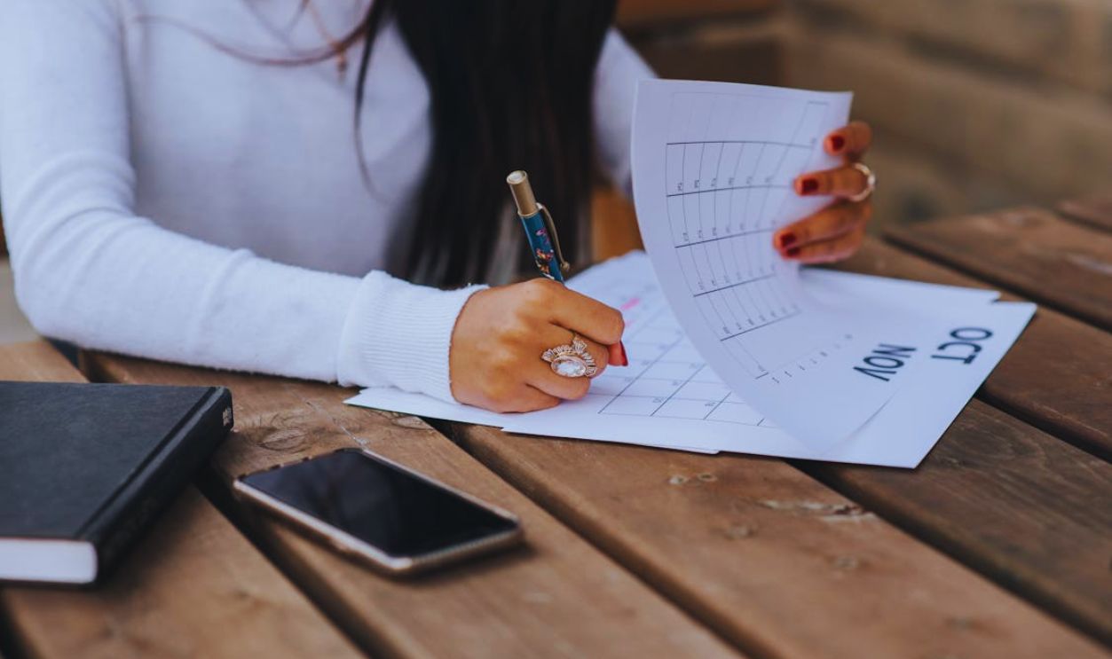 Crop woman taking notes in calendar