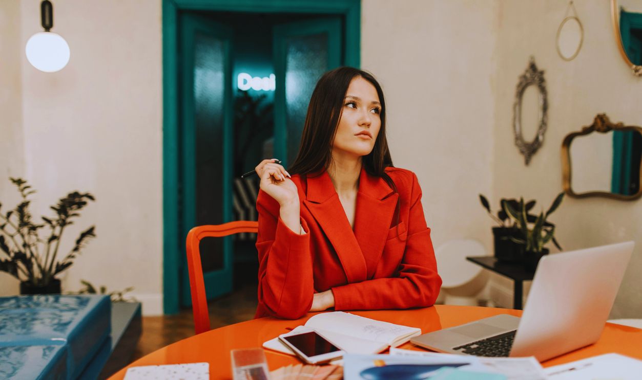 Woman in Red Blazer Sitting by the Orange Table