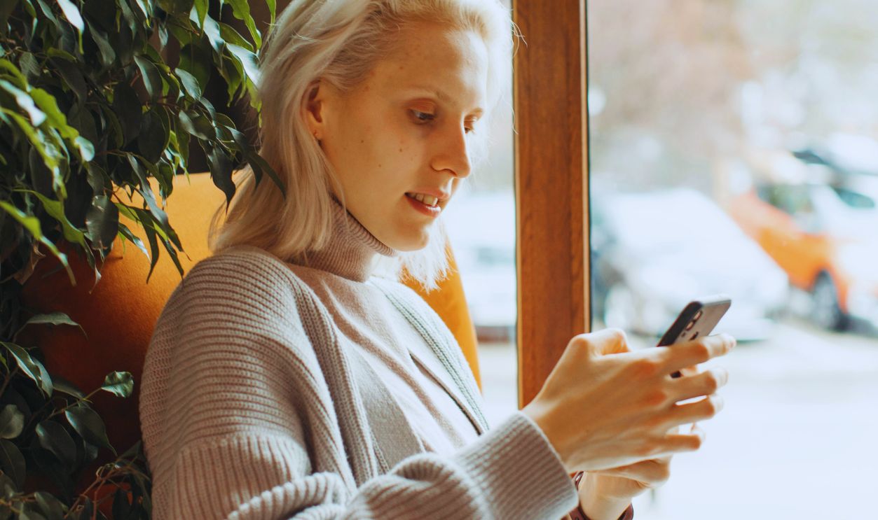 Woman in Gray Long Sleeve Shirt Holding Smartphone