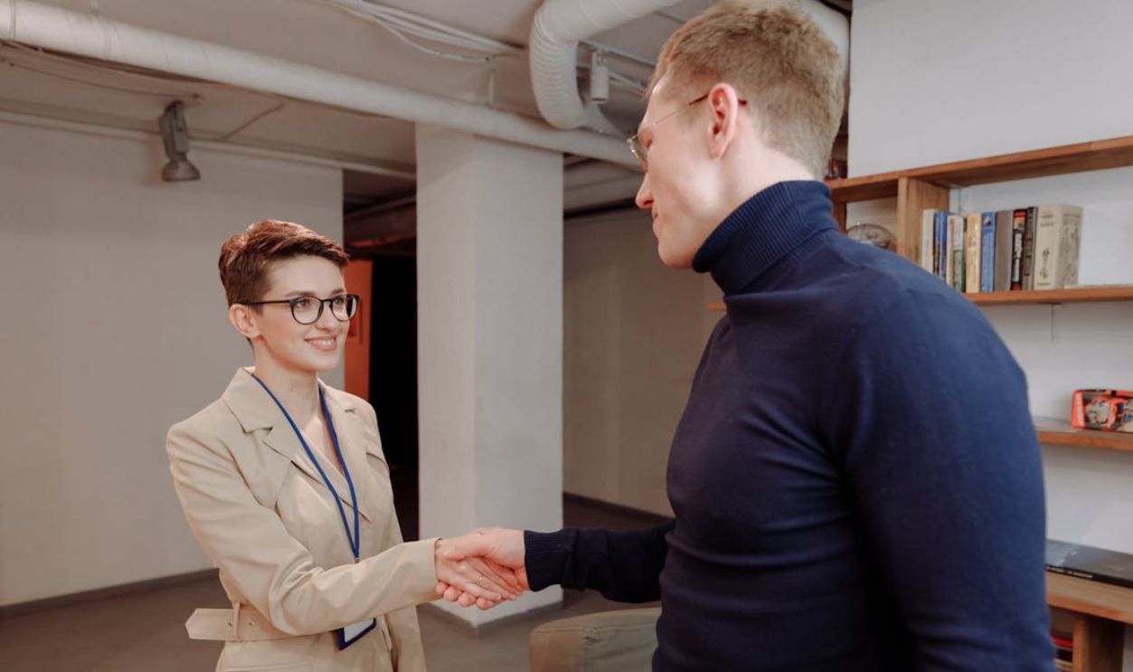 A Man and Woman Doing Handshake while Looking at Each Other