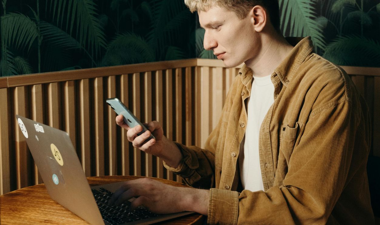 Man Using a Mobile Phone and Laptop